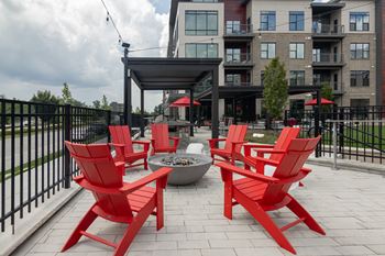A group of red chairs sitting around a fire pit on a patio